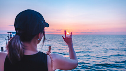 Happy asian traveler woman relax and making hand in heart love sign shape on sea beach at sunset in Koh Kood Trat Thailand Travel summer holiday vacation concept