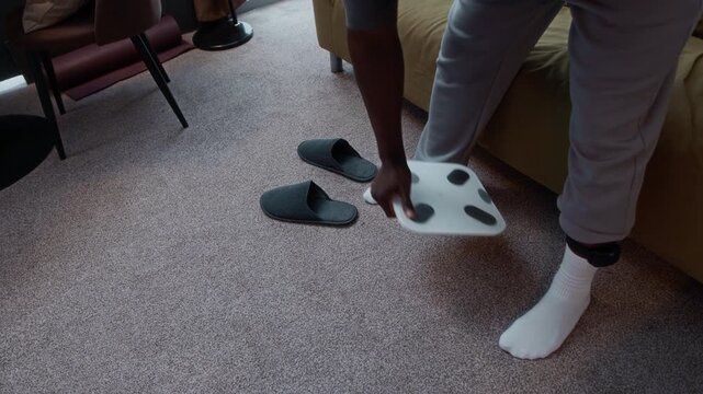 Cropped shot of unrecognizable Black man under house arrest wearing ankle monitor stepping on scales checking his weight