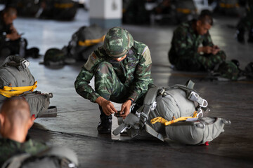 Soldier adjusting parachute gear for a fellow paratrooper before jump training.