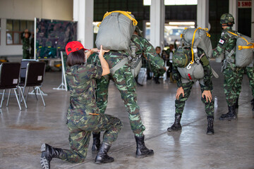 Soldier adjusting parachute gear for a fellow paratrooper before jump training.