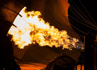 Hot air balloon filling with air using gas burner in dawn light