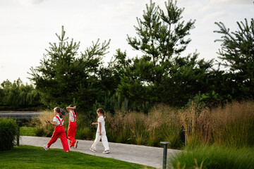 Children walking along a park pathway surrounded by lush greenery