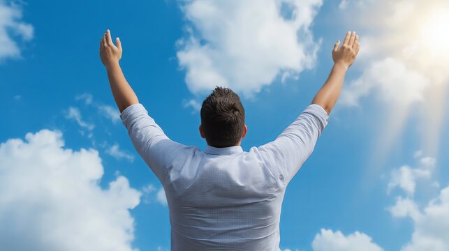 Man celebrates under the bright blue sky with arms raised in joy - Powered by Adobe