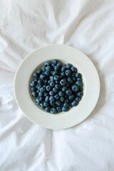 Fresh blueberries on white plate, healthy eating concept, antioxidant rich superfood image