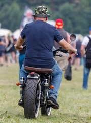 A man is riding a motorcycle in a field with a crowd of people watching