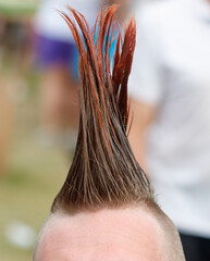 A man with a shaved head and a red and blue hair style