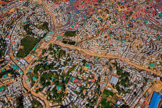 Aerial view of a densely packed settlement, buildings and roads stretch across the landscape, contrasting with patches of green, Balukhali Bazar, Chittagong Division, Bangladesh.