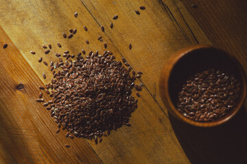 flax seeds in a wooden glass, bowl on a wooden table close-up