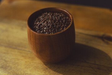 flax seeds in a wooden glass, bowl on a wooden table close-up