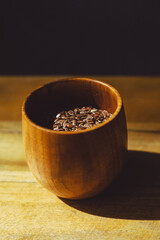 flax seeds in a wooden glass, bowl on a wooden table close-up