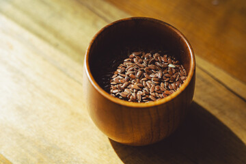 flax seeds in a wooden glass, bowl on a wooden table close-up