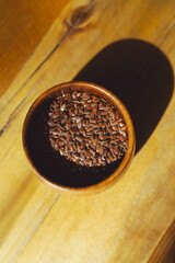flax seeds in a wooden glass, bowl on a wooden table close-up