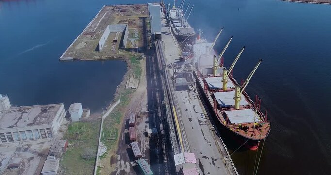 Grain enters the ship via the elevator. Loading the ship with grain in the port. The ship is loaded with grain. Grain loading in hold of bulk carrier ship with elevator crane. Port grain elevator. 