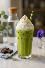 Iced matcha latte with whipped cream topping and straw on marble counter

