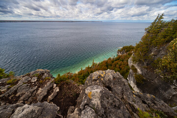 Lake Huron turquoise waterfront surrounded by Limestone Rocky Cliffs with Trees, autumn day landscape