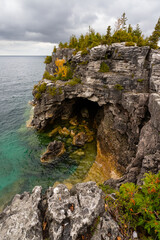 Rugged Rocky Cliff with Grotto Cave Entrance Surrounded by Turquoise Water of Lake Huron