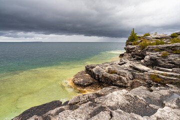 Rugged Rocky Limestone Cliff Surrounded by Turquoise Water of Lake Huron