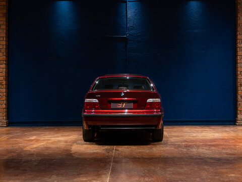 Rear view of a classic red BMW 325i E36, Vintage German sports sedan in a studio

