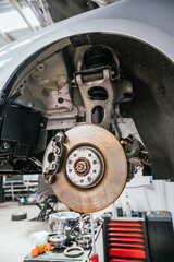 Exposed brake and suspension system on car undergoing repair