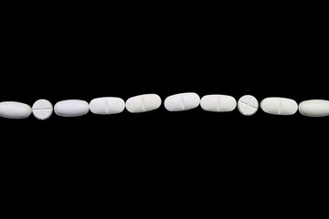 Chain of pills or white medications on a black background
