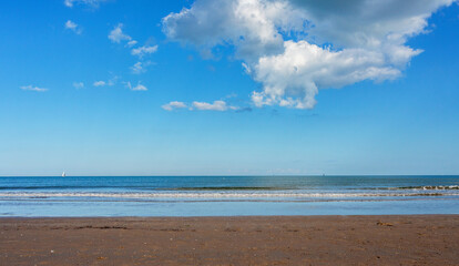 Scenic beach Chioggia, Veneto  Adriatic Sea  landscape with soft waves lapping at the shore under a bright blue sky filled with fluffy clouds, creating a serene and tranquil atmosphere for relaxation