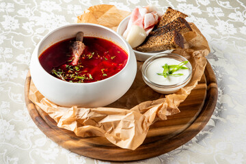 Rustic serving of traditional borscht soup with bone, herbs, rye bread, garlic, bacon, and sour...