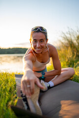 Young woman stretching legs after training outdoors in summer
