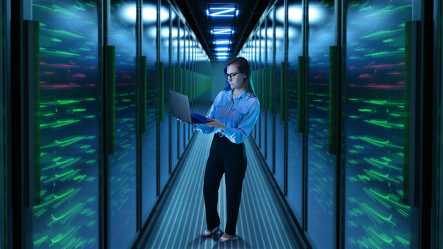 Woman with laptop standing in glowing 3D server corridor. Concept of data center security, IT operations, cybersecurity team, digital infrastructure, and cloud technology.