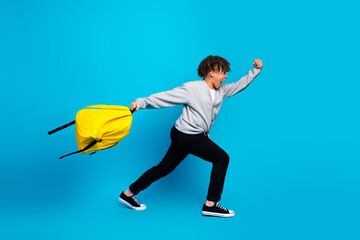 Dynamic youth running with a vibrant yellow backpack against a blue background, symbolizing...