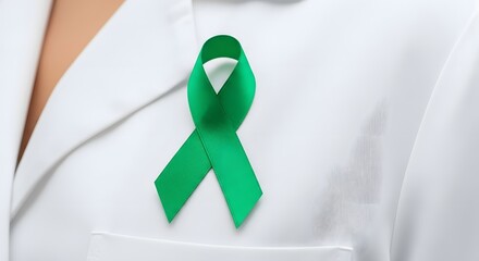 Close-up of a green ribbon pinned to a white lab coat, symbolizing awareness and support.