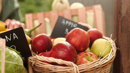 Close up shot of fresh ripe apples in basket at food market. Many apples on market counter outdoors. Fruits and vegetables on counter at market. Retail. Groceries on display
