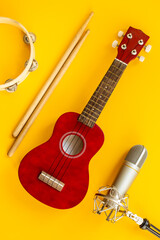 Recording music in a studio. Musical instruments for band - small guitar, drumsticks and tambourine - with studio microphone