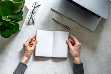 Hands holding notebook near headset and laptop, top view. Customer support equipment at call center. Online conference. Online education concept