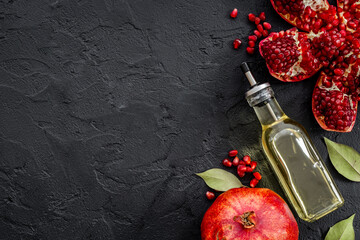 Glass bottle of pomegranate seed oil in a glass bottle and fresh fruit on a table, top view