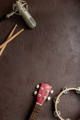 Recording music in a studio. Musical instruments for band - small guitar, drumsticks and tambourine - with studio microphone