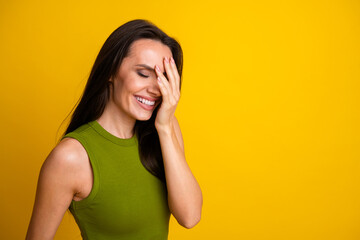 Attractive young woman laughing against vibrant yellow background, expressing happiness and joy in...