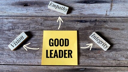 Sticky note boldly stating Good Leader is surrounded by wooden blocks labeled Vision, Empathy, and Integrity, connected by arrows on a rustic wooden background.