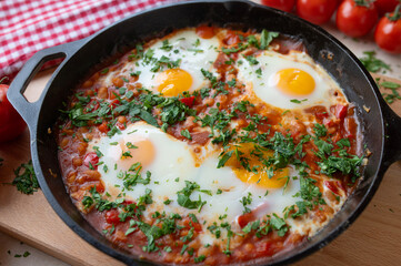 Homemade baked beans with fried eggs, sunny side up in a frying pan.