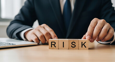 Businessperson arranging wooden blocks spelling R I S K on desk