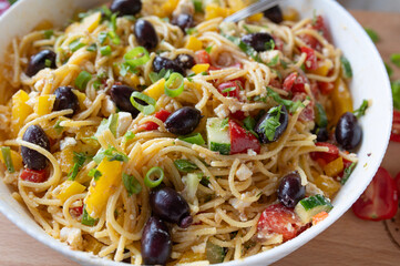 Delicious greek pasta salad with feta cheese, spaghetti noodles, peppers, cucumber, onions, tomatoes and olives, fresh and homemade cooked