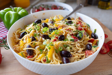 Delicious greek pasta salad with feta cheese, spaghetti noodles, peppers, cucumber, onions, tomatoes and olives, fresh and homemade cooked