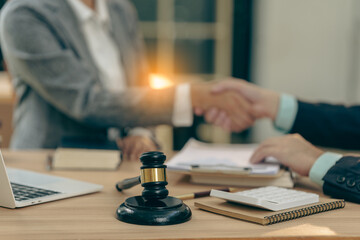 Judge's gavel with lawyer and client shaking hands after successful contract negotiations. Providing legal advice, legal services, and contract consultation to plan court cases.