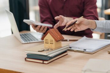 Real estate agent congratulates new buyer by presenting model home to client. Close-up of real estate agent meeting with client in office.