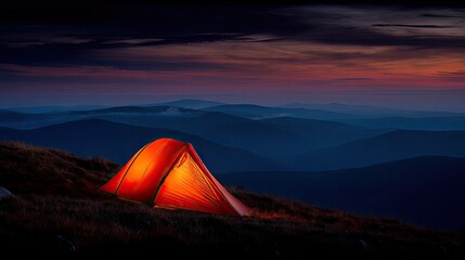 Orange tent illuminated at mountaintop dusk