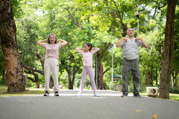 Happy Asian grandparents and granddaughter running joyfully together in a park,