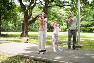 Happy Asian grandparents and granddaughter running joyfully together in a park,