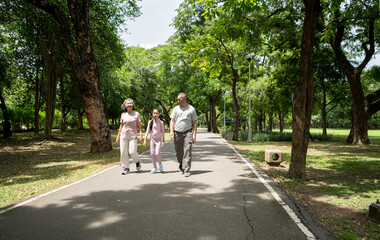 Happy Asian grandparents and granddaughter exercise joyfully together in a park