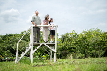 Happy Asian grandparents enjoying a picnic with their granddaughter in a green park