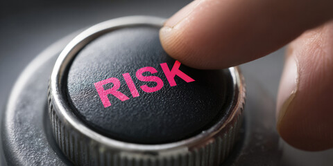Finger pressing black button labeled RISK symbolizing danger or uncertainty.