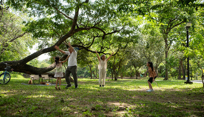 Happy Asian grandparents enjoying a picnic with their granddaughter in a green park